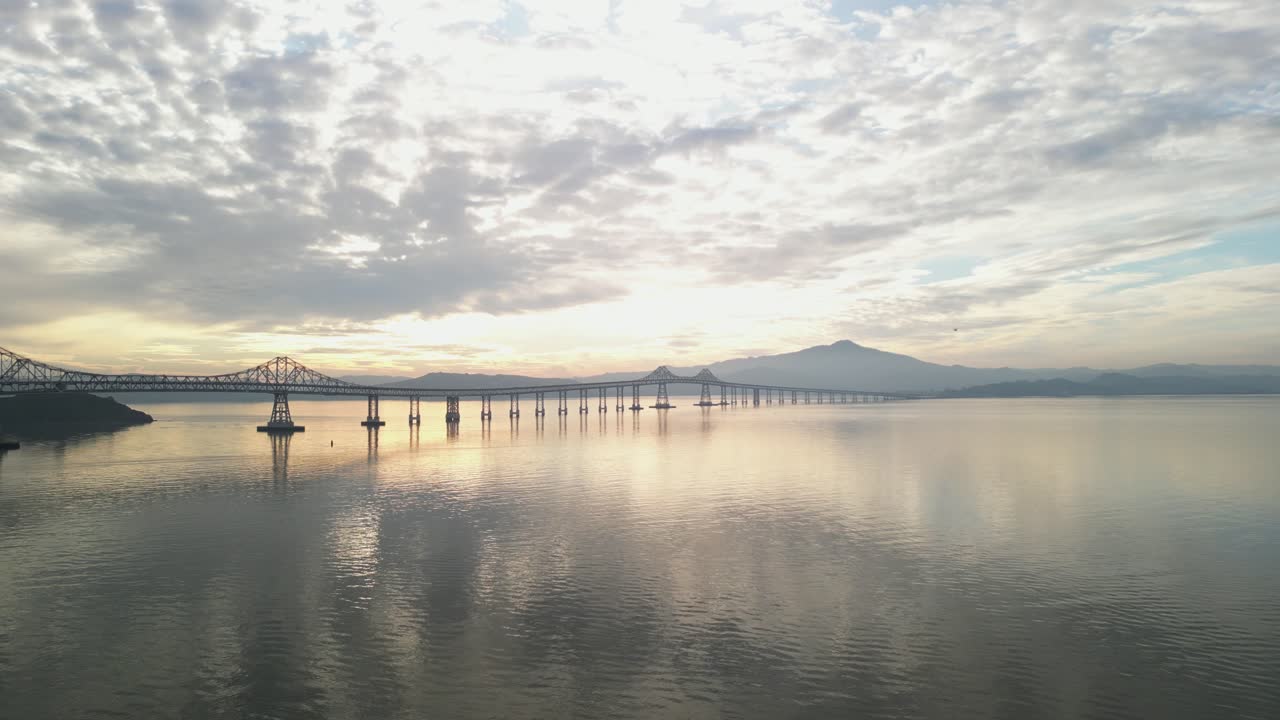 Aerial drone footage captures the Richmond–San Rafael Bridge stretching across the bay near Point Molate Beach.