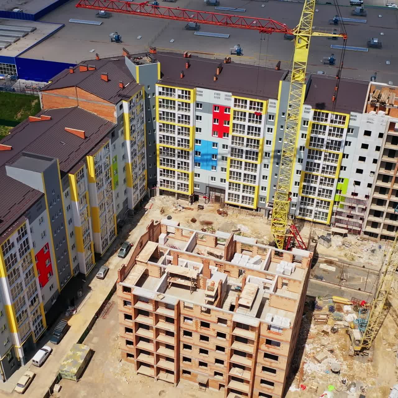 Construction of a multi-storey apartment building. Building of a multi-quarter houses in the city. Tower crane on a construction site. Aerial view