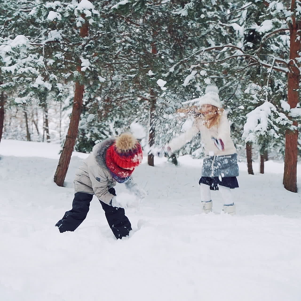 Outdoor family fun on Christmas vacation. Boy and girl play snowballs. Winter clothing. Slow motion.