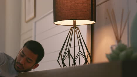 man lying in bed next to a lamp