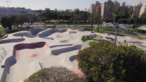 parallax shot over trees of a big skate park with grass around