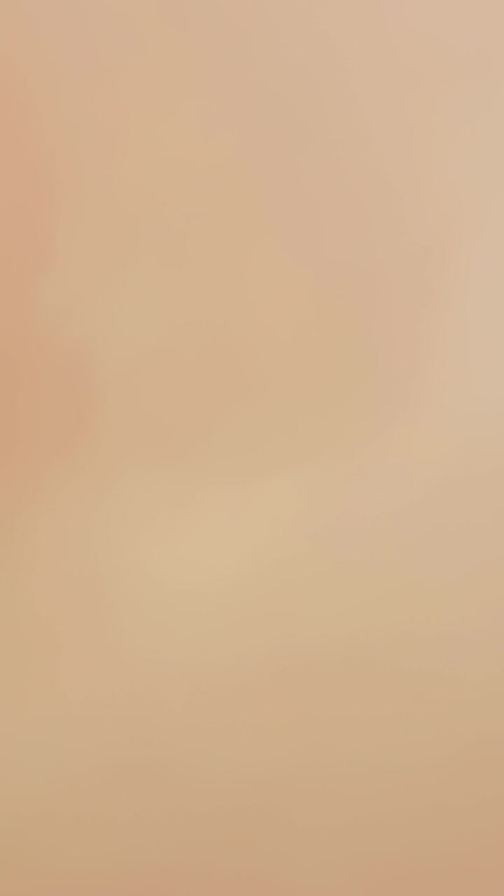 Video verticale: Primo piano catturato con la fotocamera del telefono di una superficie beige dopo un tocco, che mostra lievi cambiamenti di tonalità.