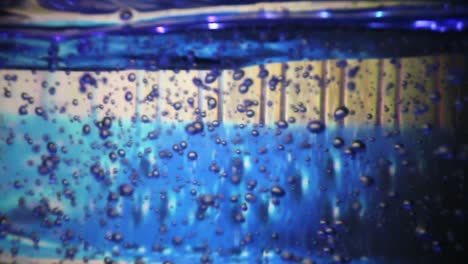 vista de gran ángulo de una gran botella de desinfectante de manos como fondo es muy colorida - las luces debajo de la botella cambian de color para resaltar las burbujas de aire