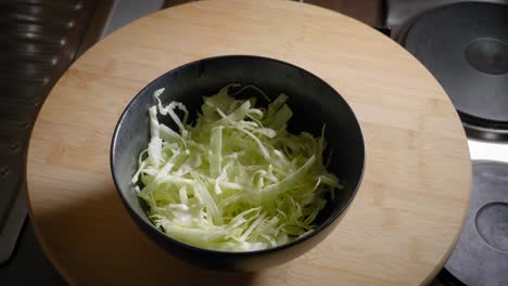 male hand is adding and removing a bowl of sliced cabbage from a table, cooking scrambled eggs