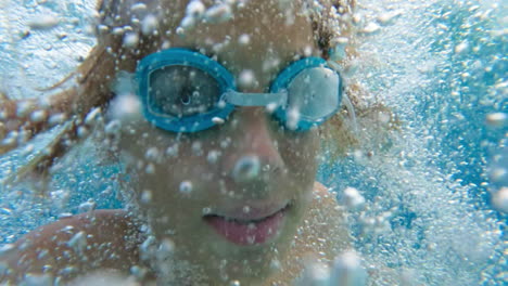 child swimming underwater with goggles