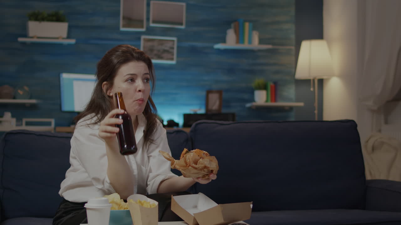 Young person enjoying takeaway burger and beer after work