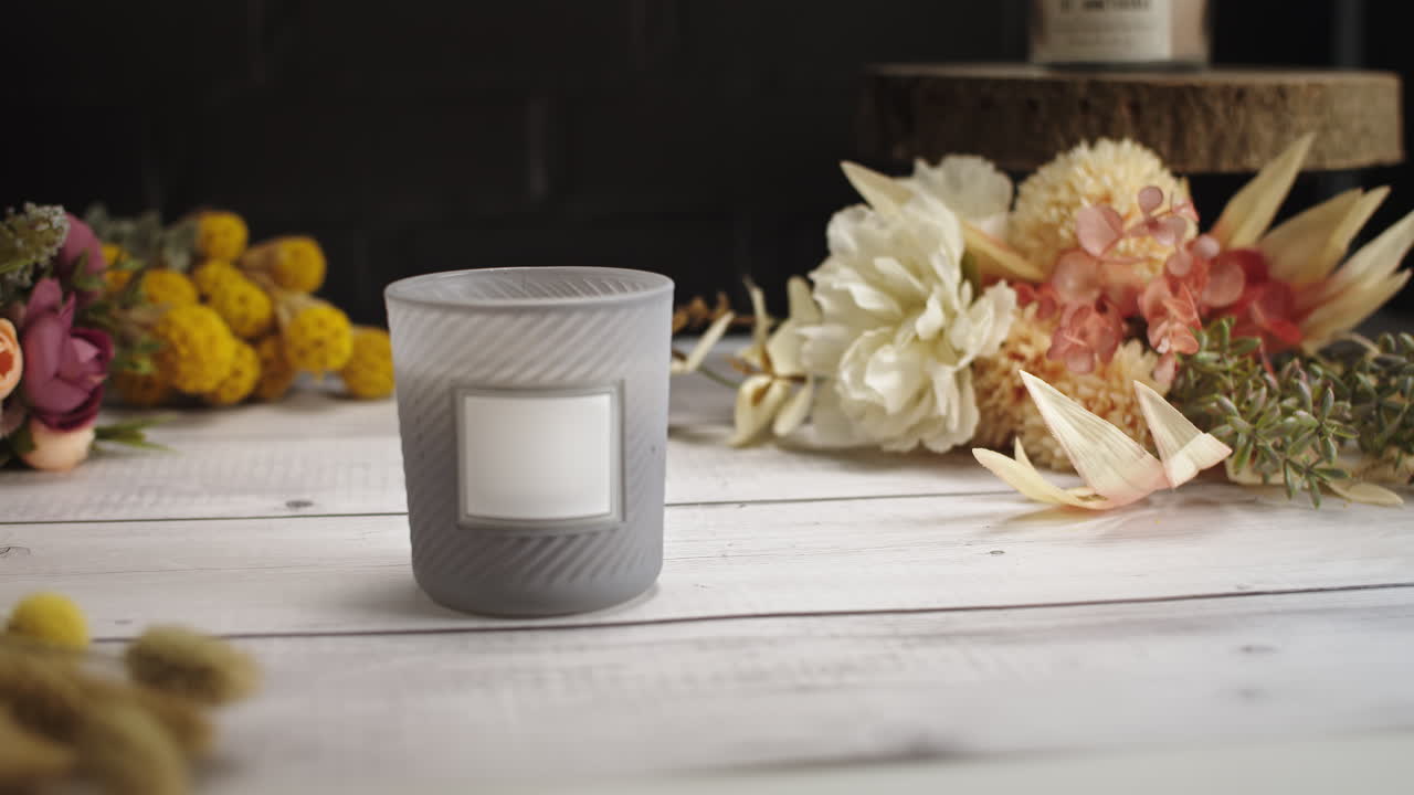 Bougie sur une table en bois blanc devant un mur de briques noires