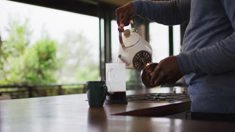 Mittelteil-Eines-Afroamerikanischen-älteren-Mannes-In-Der-Küche,-Der-Kaffee-In-Der-Kanne-Kocht