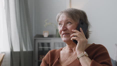 senior woman calling by smartphone sitting at home 1