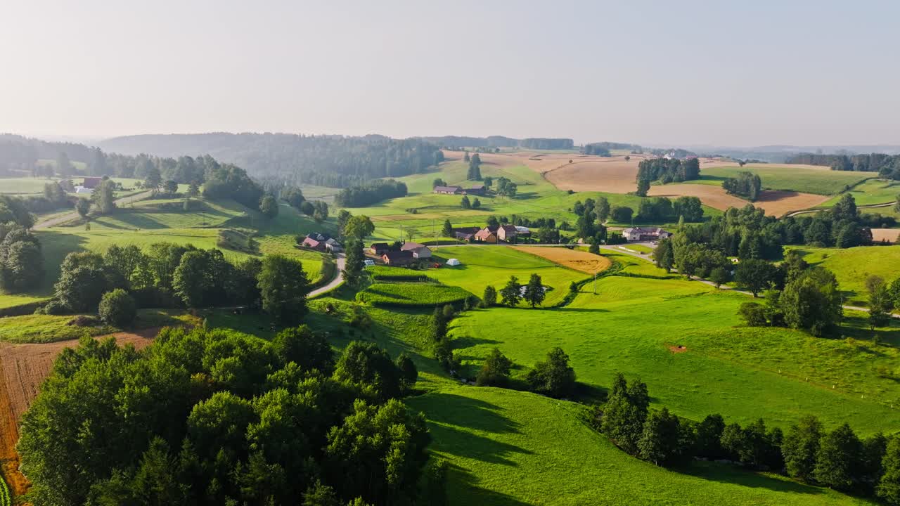 Peaceful morning landscape of rolling fields and village houses in Poland