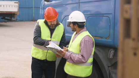 Chef-Und-Arbeiter-Mit-Westen-Und-Schutzhelmen-Organisieren-Eine-LKW-Flotte-In-Einem-Logistikpark,-Während-Sie-Ein-Dokument-Konsultieren-9