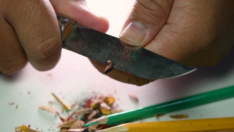 Footage-of-hands-slowly-sharpening-a-pencil-and-some-coloured-pencils-with-a-sharp-knife