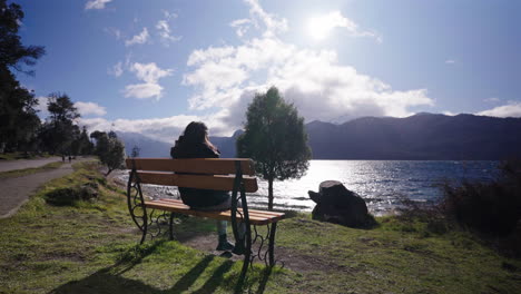 a girl sits quietly on a wooden bench in villa traful, argentina, surrounded by natural beauty