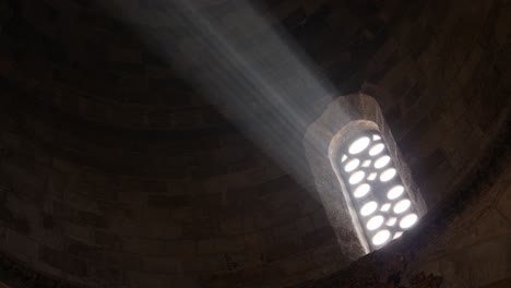 close-up of a bright light shining through an old church window beaming through the darkness of the cathedral