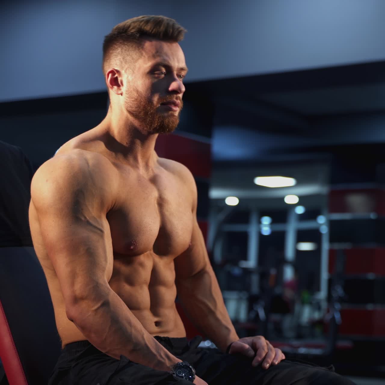 Sportivo muscoloso che solleva un manubrio in palestra. Atleta forte che si allena e riposa. Pratica di costruzione del corpo e dei muscoli per una buona forma fisica