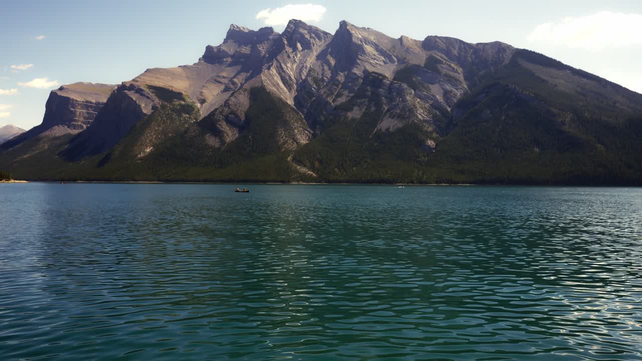 lago minnewanka con vistas a la montaña y gente remando en canoa al fondo