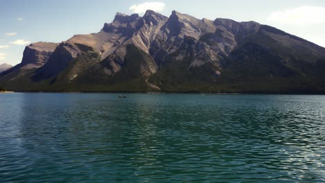 See-Minnewanka-Mit-Bergblick-Und-Leuten,-Die-Im-Hintergrund-Ein-Kanu-Rudern