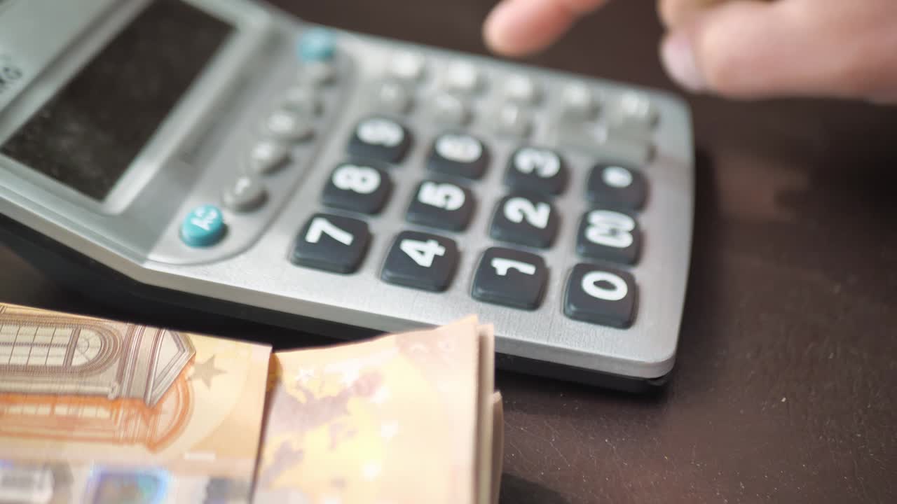 hombre cuenta a mano los gastos o los ingresos en una calculadora