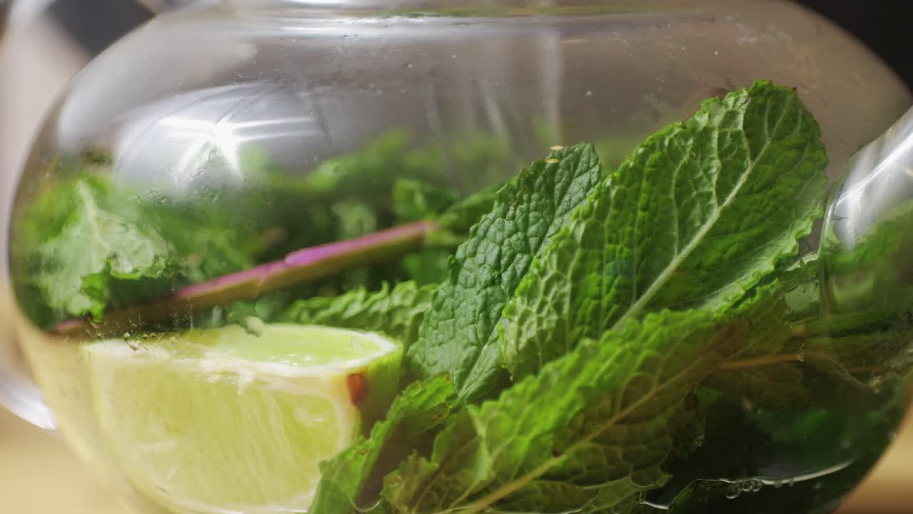 Teapot of fresh mint moroccan tea with lime, tea pot close up with pouring boiling water.