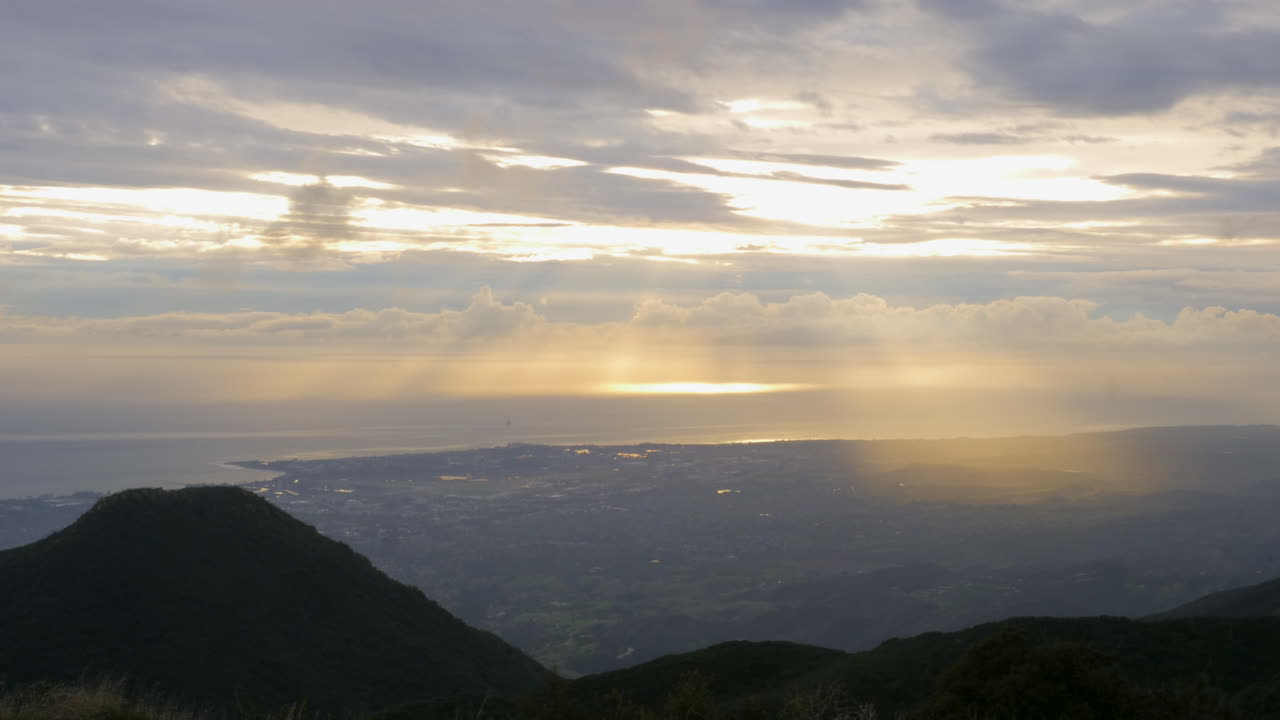 캘리포니아 중부의 태평양 연안에 있는 마을 위로 구름 사이로 움직이는 태양 광선