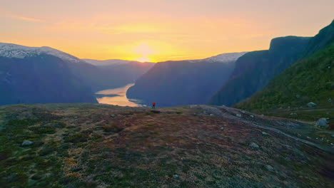 aerial drone shot flying over mountain top reveals beautiful scenery of fjord surrounded by mountain range in aurland, norway
