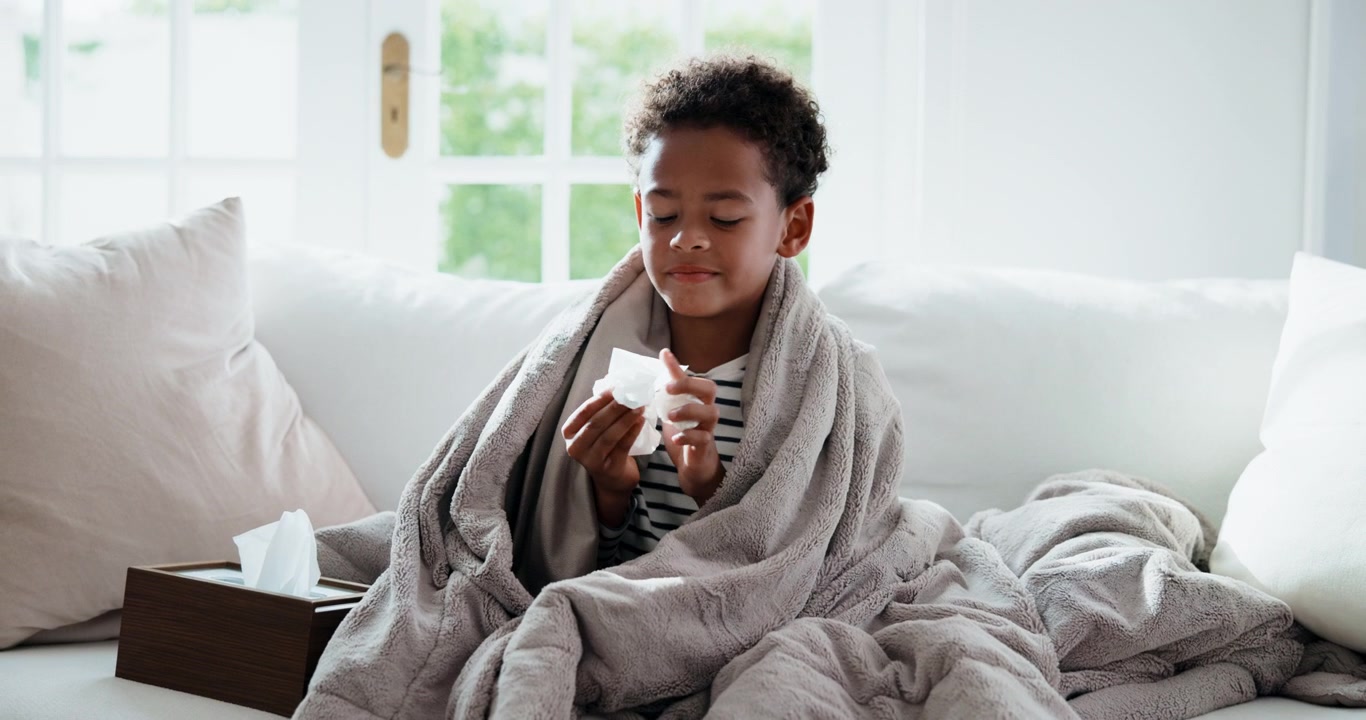 Young Boy Wrapped in Blanket Blowing Nose with Tissue