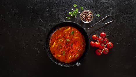 cinemagraph loop. cocinar pasta penne con salsa de tomate y albahaca en una sartén de hierro fundido.