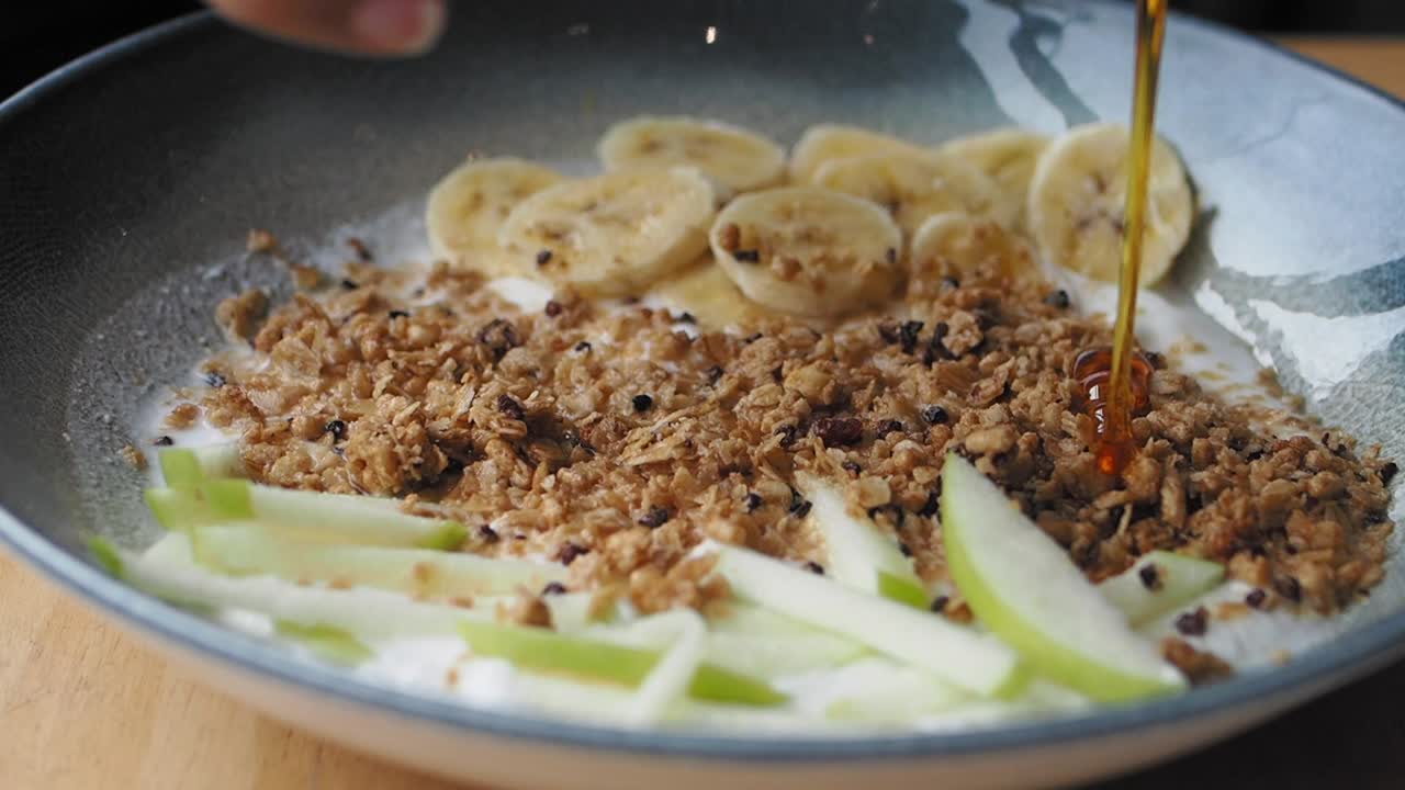 un plato de granola saludable con miel, plátanos y manzanas