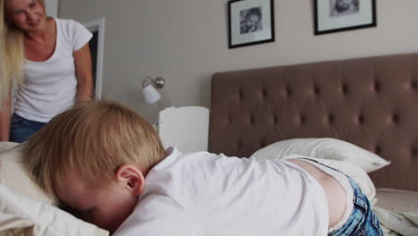 Young-mother-and-father-with-her-2-years-old-little-son-dressed-in-pajamas-are-relaxing-and-playing-in-the-bed-at-the-weekend-together,-lazy-morning,-warm-and-cozy-scene.-Pastel-colors,-selective-focus