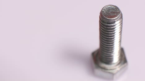 rotating galvanized metallic screw close-up. stainless steel bolt isolated on white background. copy space.