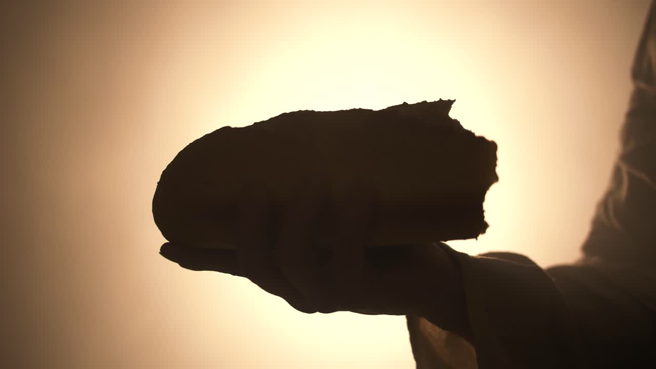 Jesus Christ holding bread in glowing, bright light. Representation of communion, last supper, Christian sacraments and Jesus as the bread of life.