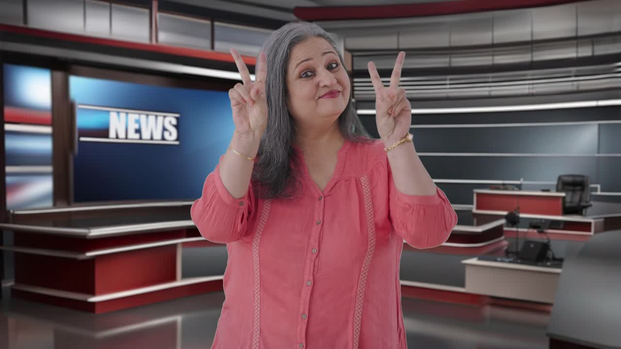 feliz periodista india senior mostrando el signo de la victoria