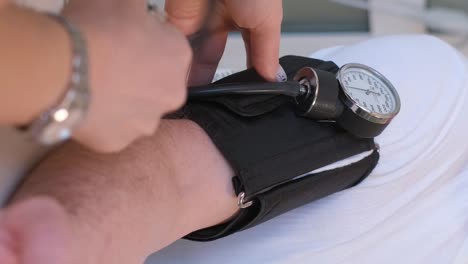 zoom in shot of young male therapist in white coat measuring blood pressure of senior patient in ward of clinic