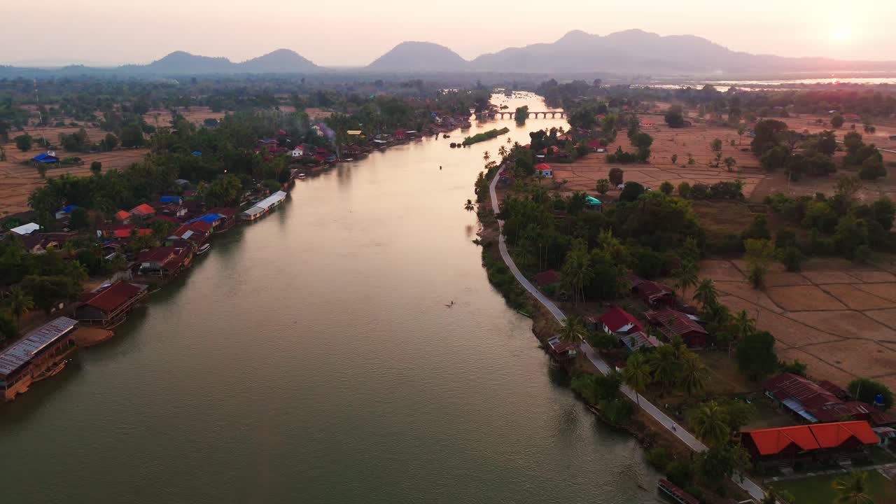 Aerial drone fly Laos 4000 Islands village, sunset reflection over Mekong River, sunset mountain background
