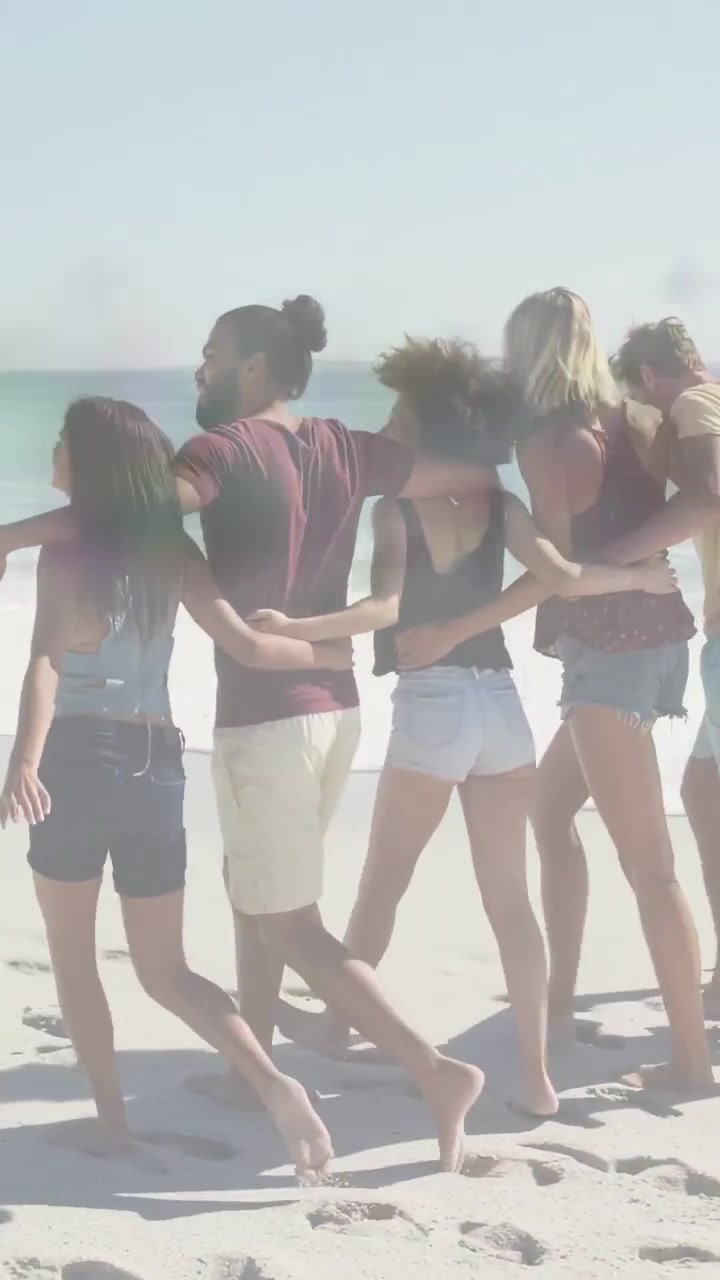 Video verticale: Gruppo che si tiene a braccetto camminando sulla riva del mare, linee glitch che svaniscono mostrando i passi per una pubblicità di viaggio.