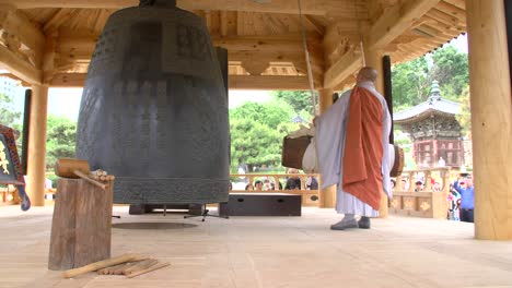 buddhist monk striking large bell