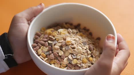 child's hands holding a bowl of cereal