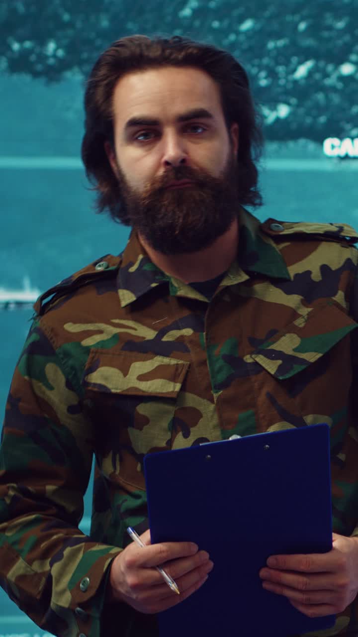 Uomo barbuto in uniforme mimetica che scrive su un blocco appunti