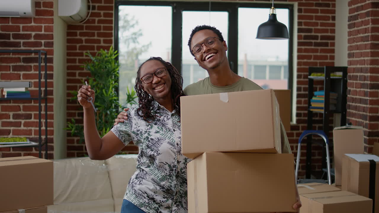 Portrait of african american couple showing apartment keys on camera