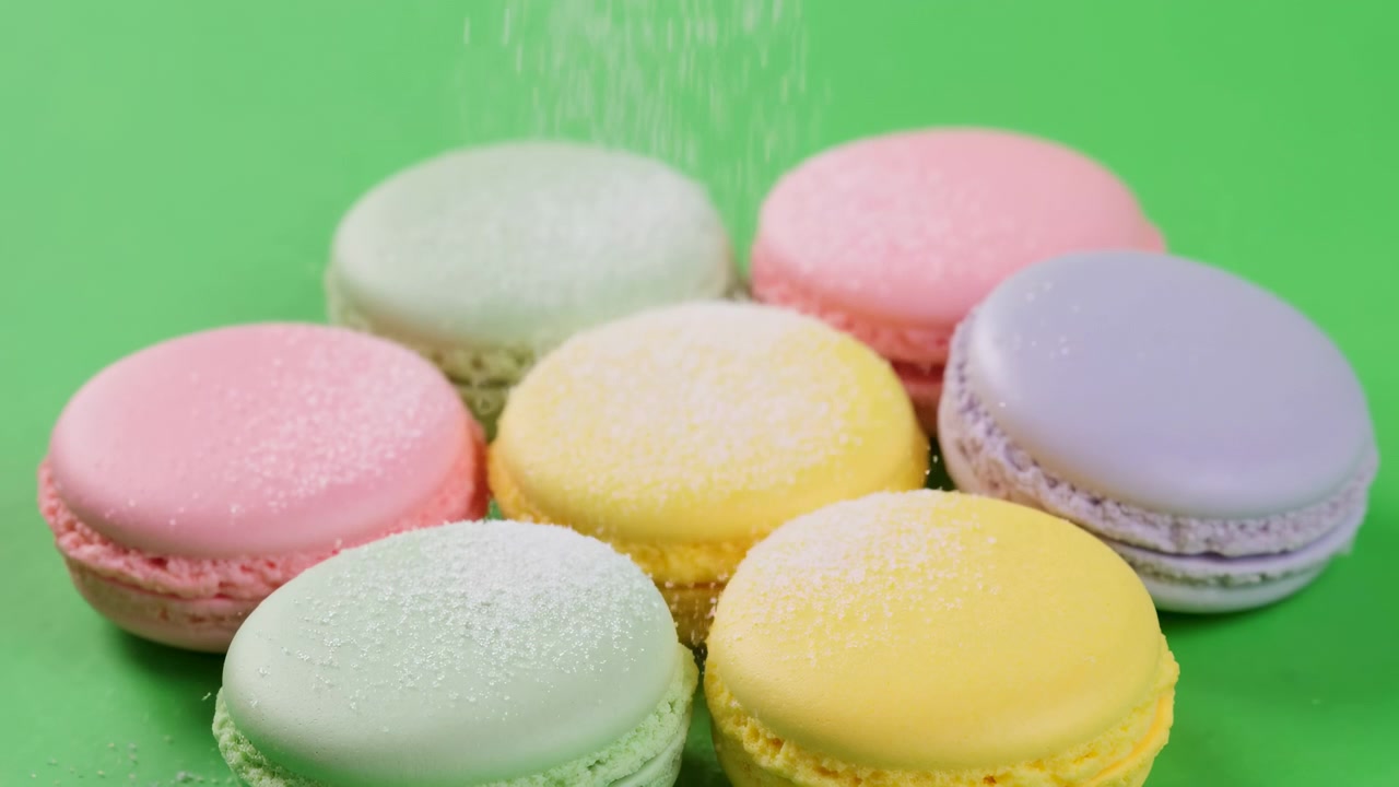 Pastel Macarons On Green Background, Bakery Display Showing Delicate French Meringue Cookies Dusted