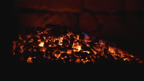 Fiery-coals-in-dark-stove,-nighttime-heat-source-close-up