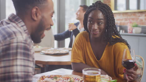 una joven pareja sonriente en una cita disfrutando de una pizza en un restaurante juntos haciendo un brindis