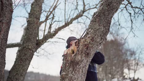 Chico-Con-Auriculares-Mientras-Corta-El-Tronco-De-Un-árbol-Con-Una-Motosierra