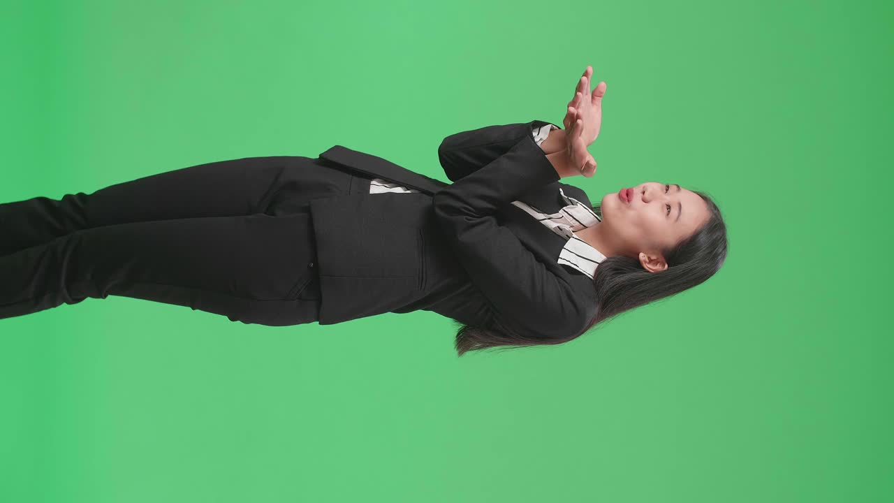 Side View Of An Asian Business Woman Blowing Kisses And Smiling In The Green Screen Studio