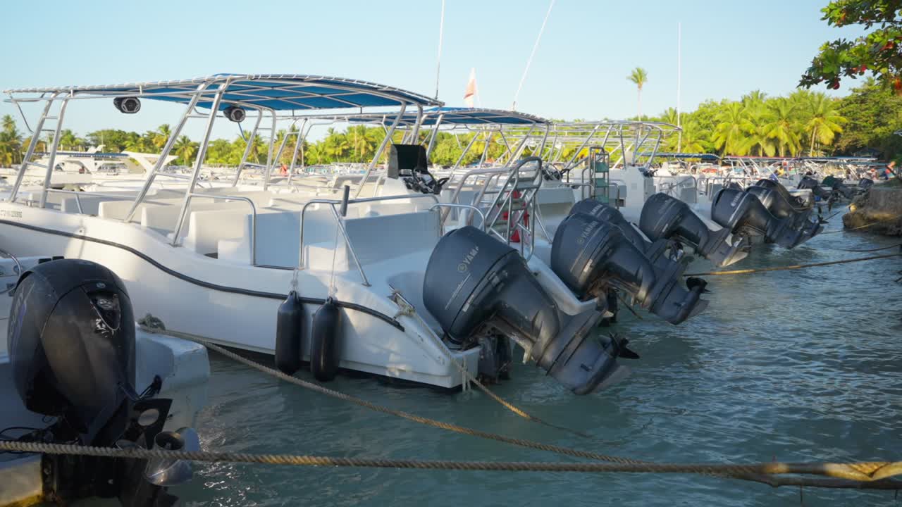 해가 지는 동안 열대 해변의 항구에 정박한 고속 여행 보트의 상승 모터의 뒷면