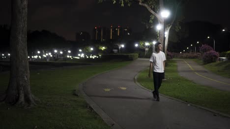 man walking in the park alone at night at east coast park, singapore with bright street lights