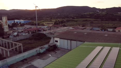 establisher aerial view of green warehouse with solar panels and wind turbine