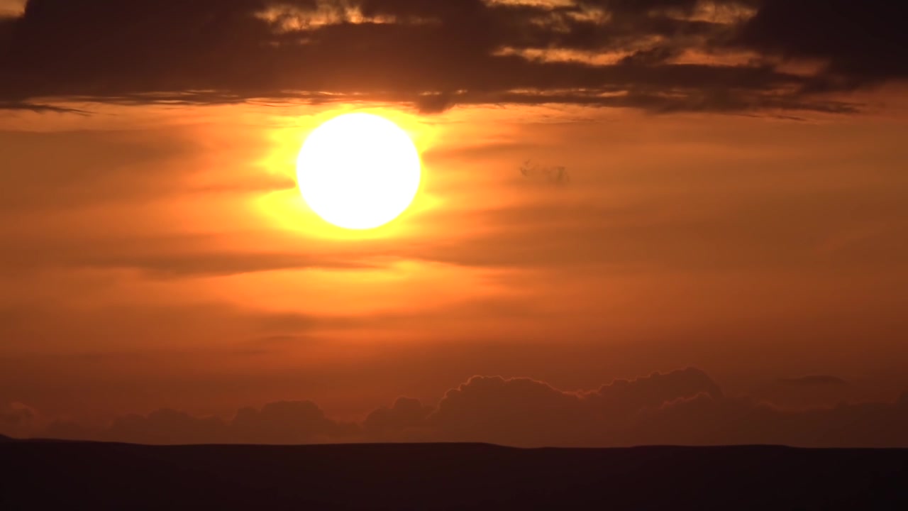 Dramatisk solnedgang med solen der går ned bag mørke skyer