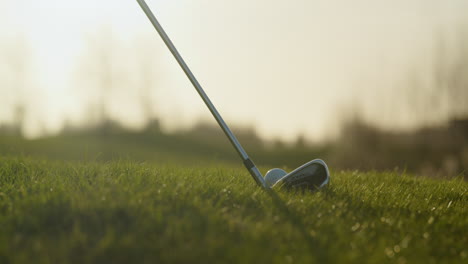 placing golf club behind ball, low angle close up at golden hour slomo