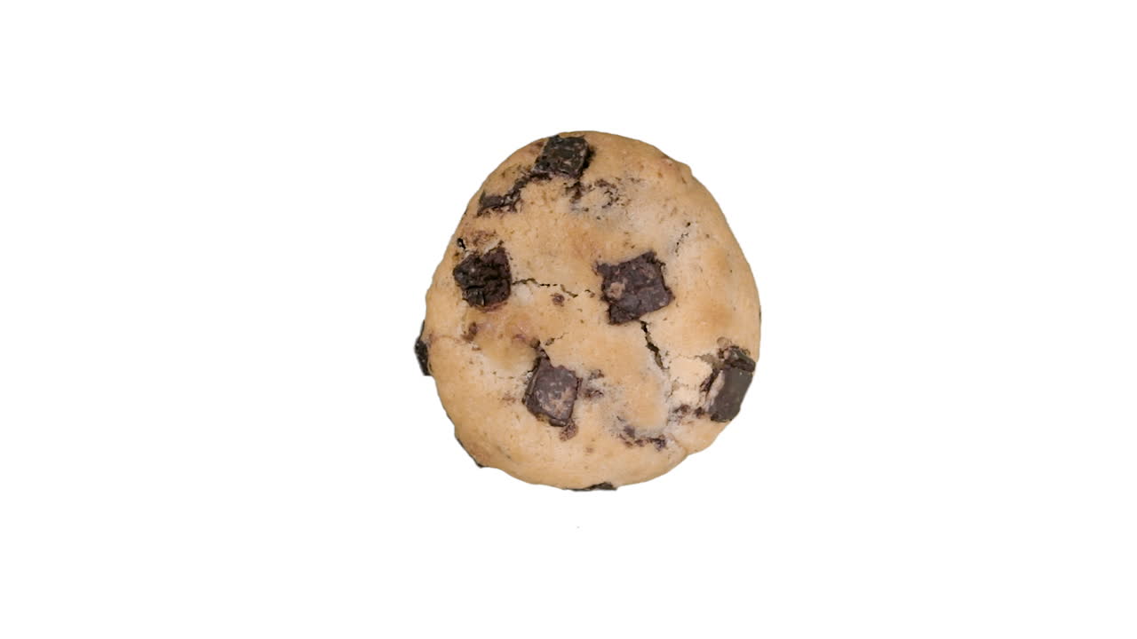 Freshly cooked chocolate chip cookie spinning on white background in top down view